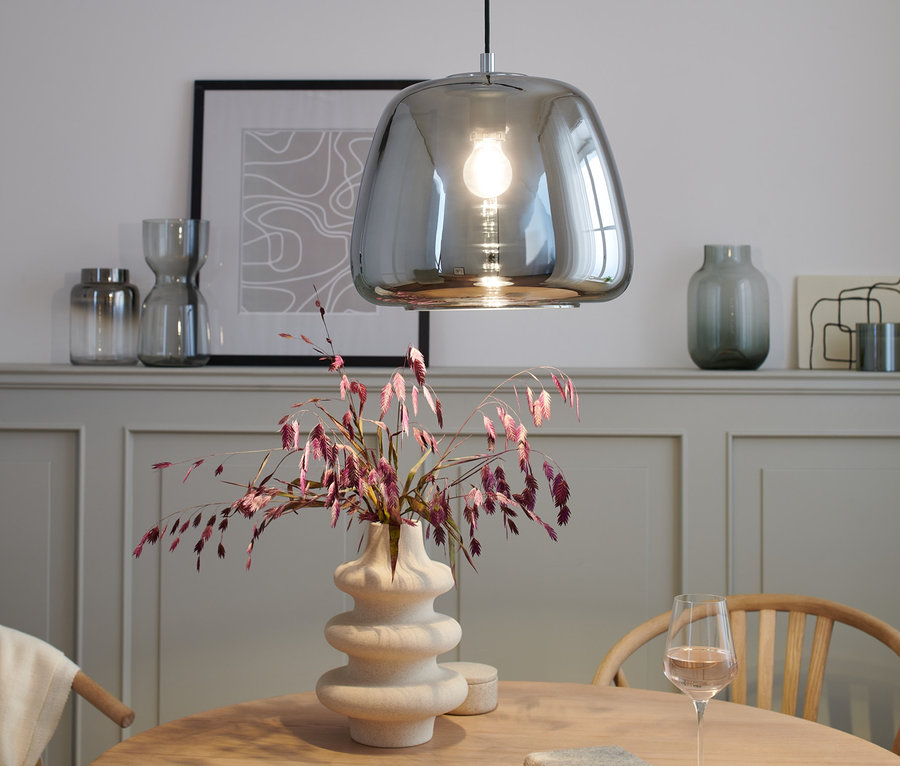 Lustre en chrome au-dessus d'une table avec vase et verre à vin.