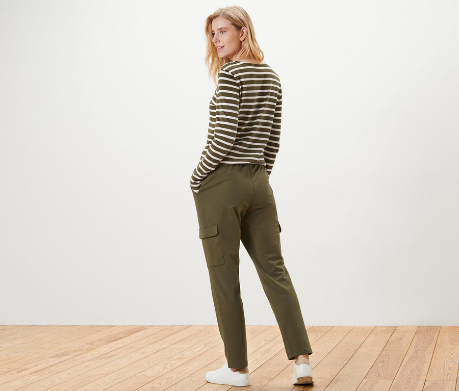 Femme posant en pantalon de jogging kaki à poches cargo et haut rayé.