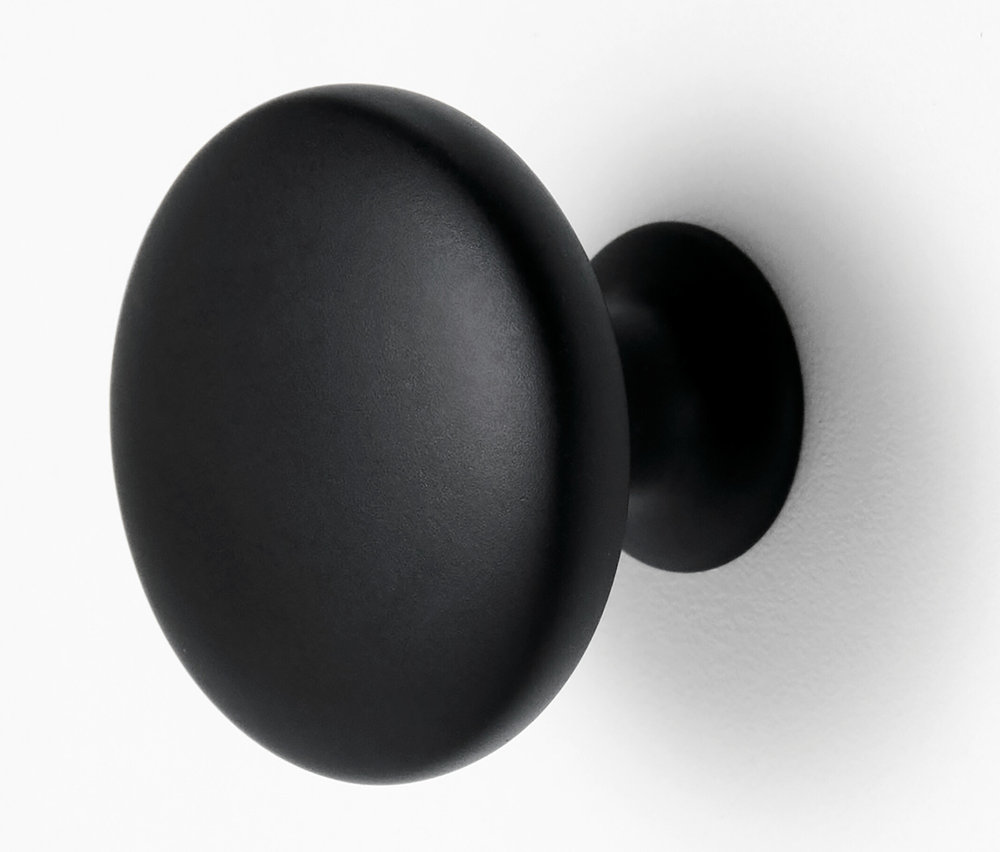 Gros plan d'un bouton de meuble rond noir sur un fond blanc.