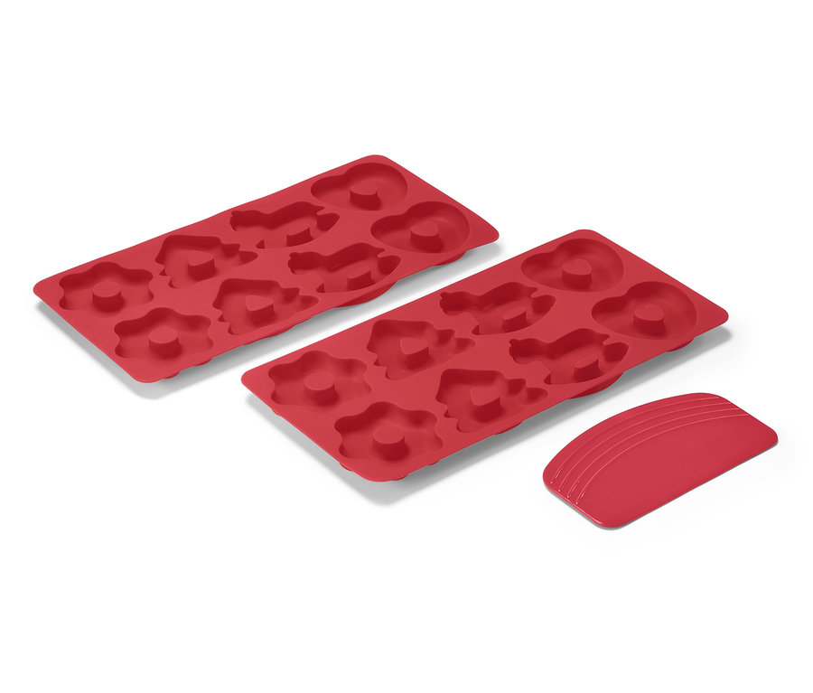 Deux tapis de cuisson rouge pour mini pains d’épices et un grattoir sur fond blanc.