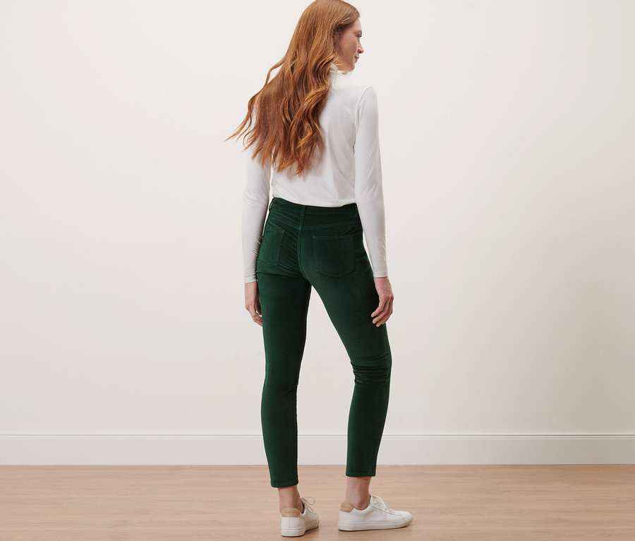 Femme debout, vue de dos, portant un pantalon en velours vert foncé.