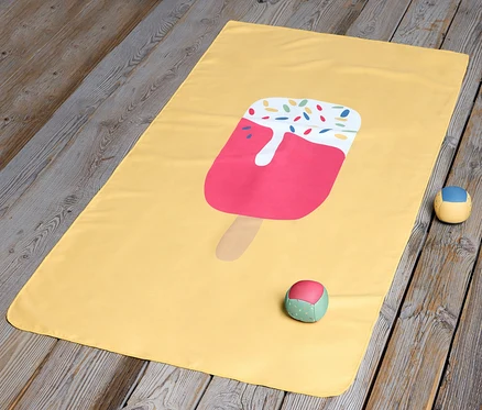 Une serviette microfibre jaune pour enfants avec un motif de glace posée sur un plancher en bois.