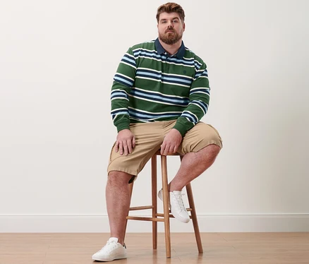 Un homme est assis sur un tabouret, portant un polo manches longues et un short cargo couleur sable.