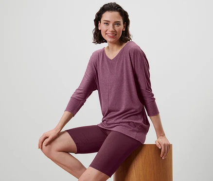 Femme assise sur un tabouret portant une chemise de yoga mauve et un cycliste de sport.