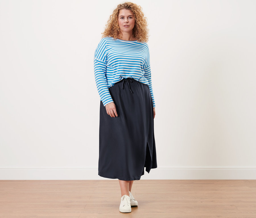 Femme posant dans un t-shirt à manches longues rayé et une jupe en jersey piqué.