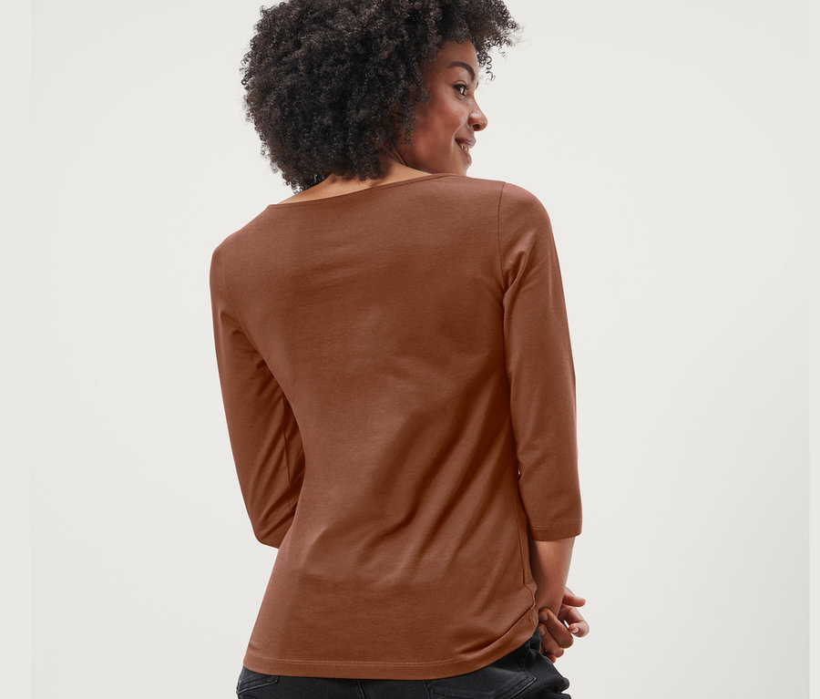 Vue arrière d'une femme avec un afro portant un t-shirt cognac à manches 3/4 et un jean noir.