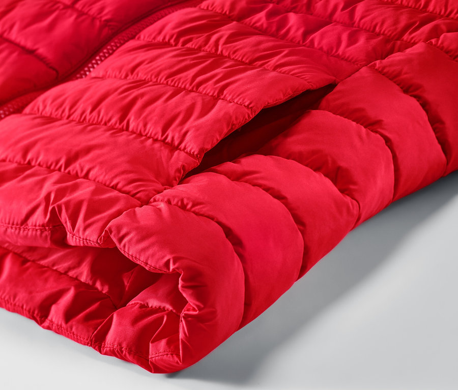 Détail d'un gilet sans manches matelassé rouge avec une poche.