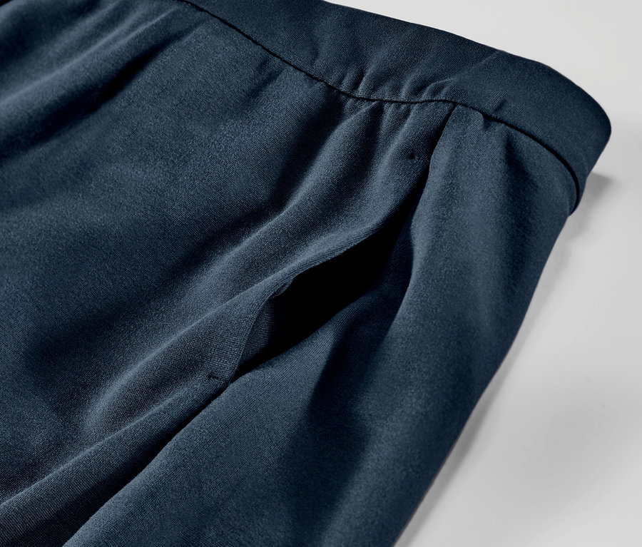 Gros plan sur un pantalon en jersey bleu marine avec passepoil et poche.