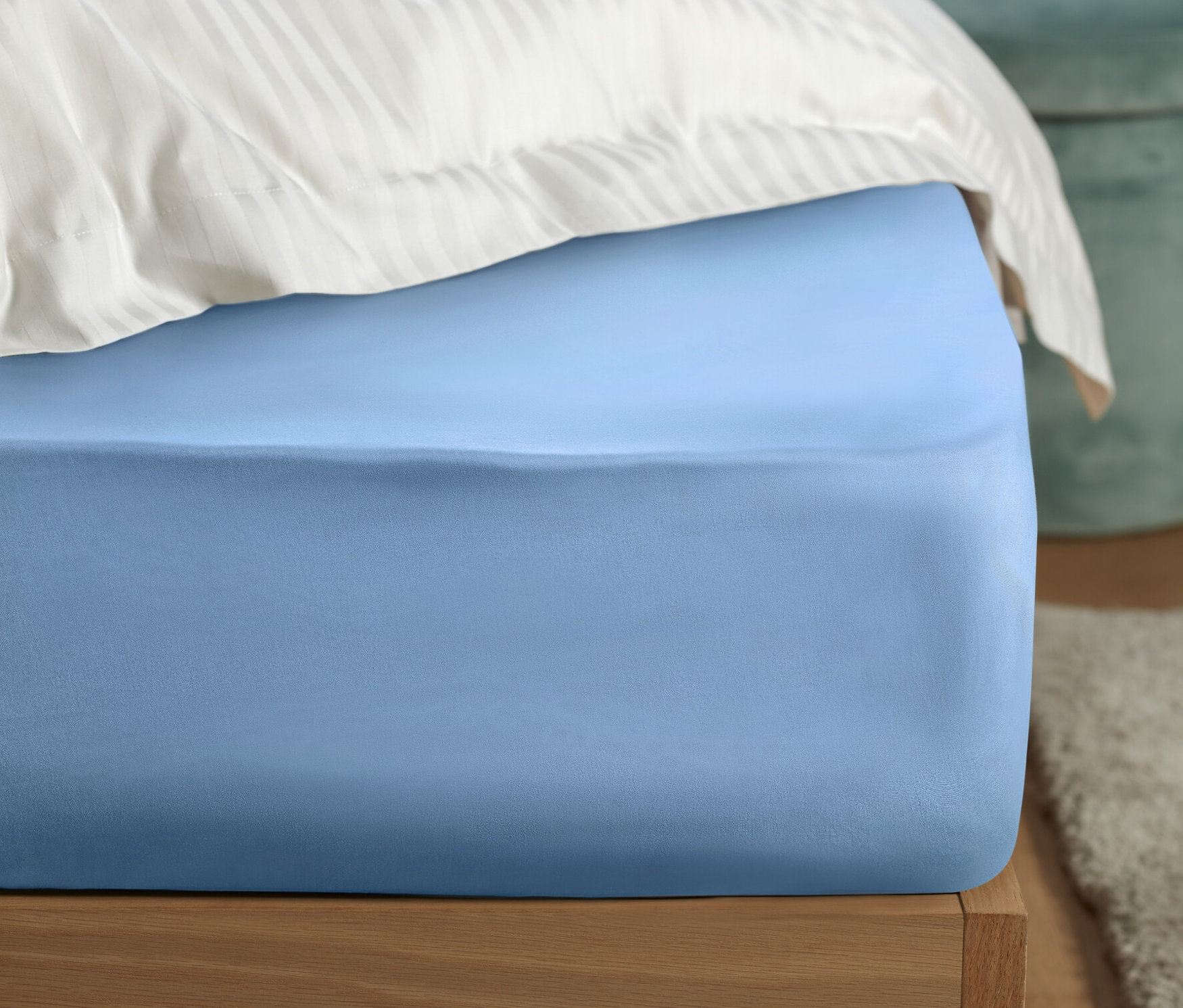 Gros plan d'un lit avec un drap-housse en percale bleu clair.