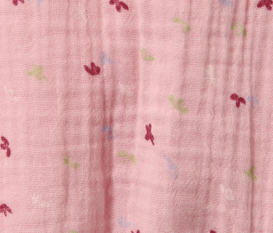 Vue détaillée d'une barboteuse pour bébé rose avec des motifs.