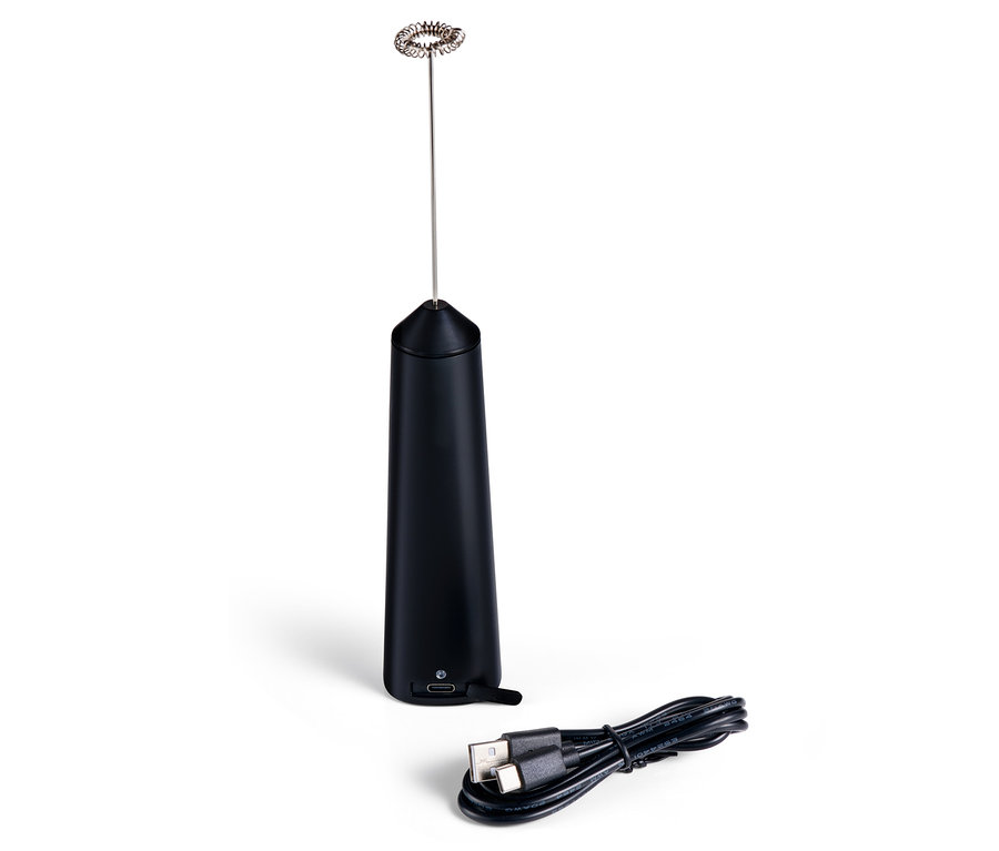 Un mousseur à lait à batterie rechargeable noir et un câble de chargement sont posés sur une surface blanche.