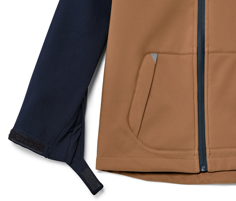 Détail d'une veste en softshell pour enfant avec un devant marron et une manche bleu foncé.