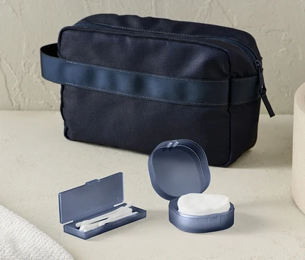 Sur la table, il y a une boîte de rangement et une trousse de toilette bleu foncé.