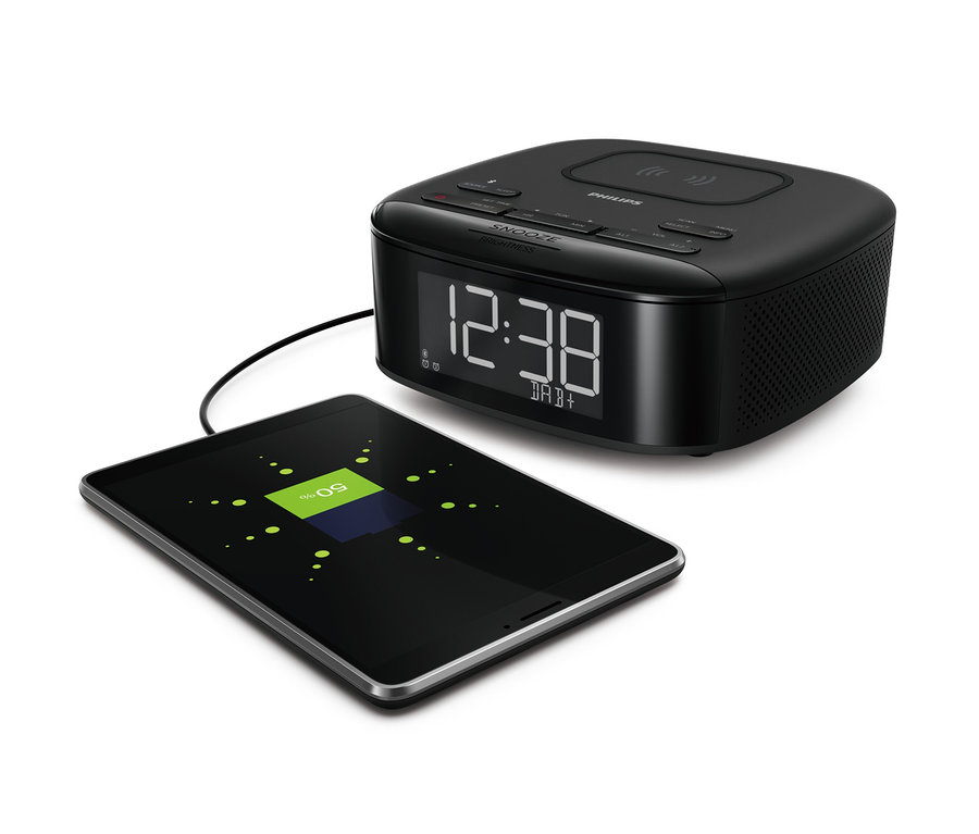Un radio-réveil DAB Philips « TAR7705 » noir et une tablette en charge.
