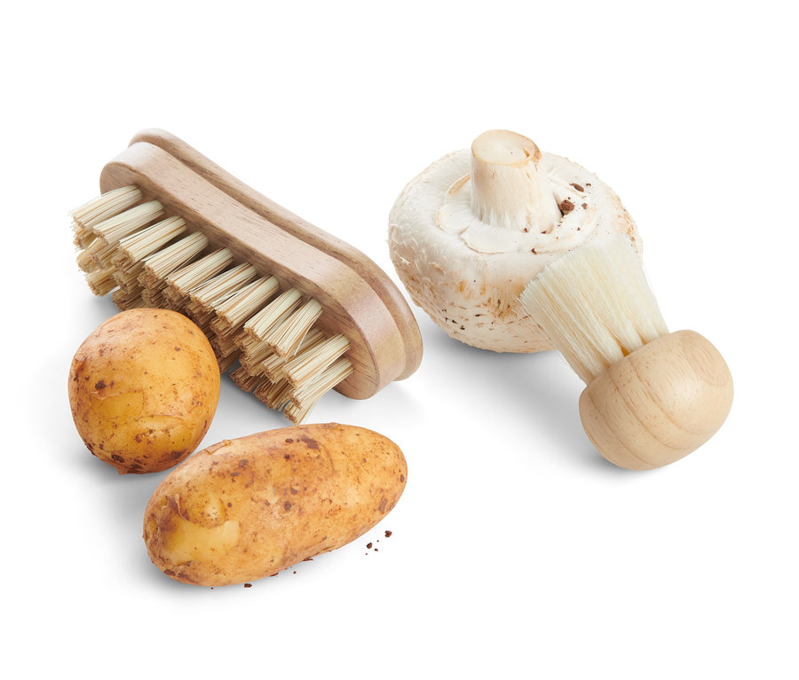 Deux pommes de terre et un champignon à côté de deux brosses à légumes.