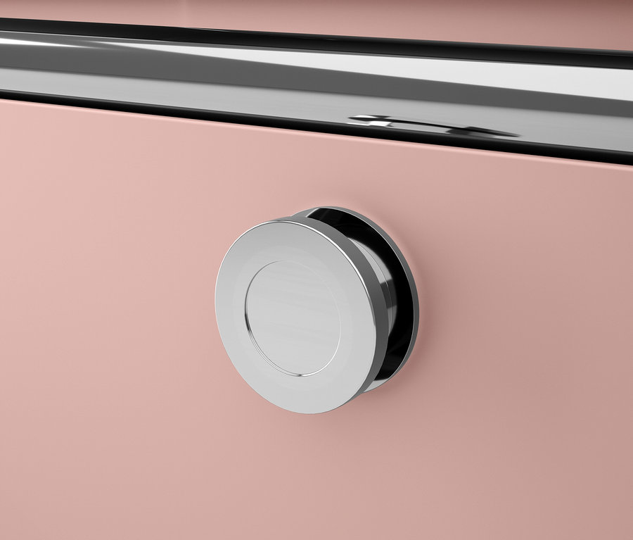 Détail d'un meuble rose avec une poignée ronde argentée.
