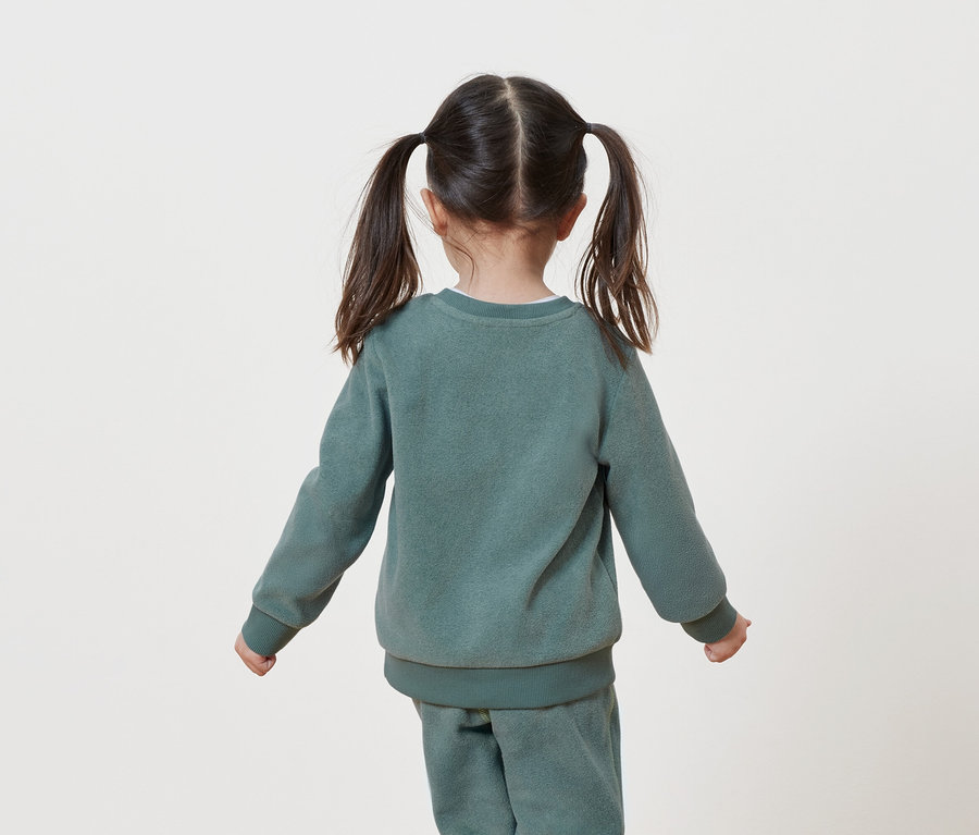 Vue de dos d'une petite fille avec des couettes dans un survêtement vert.