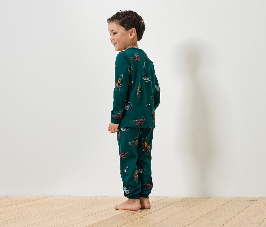 Garçon portant un pyjama vert avec un imprimé de voitures.