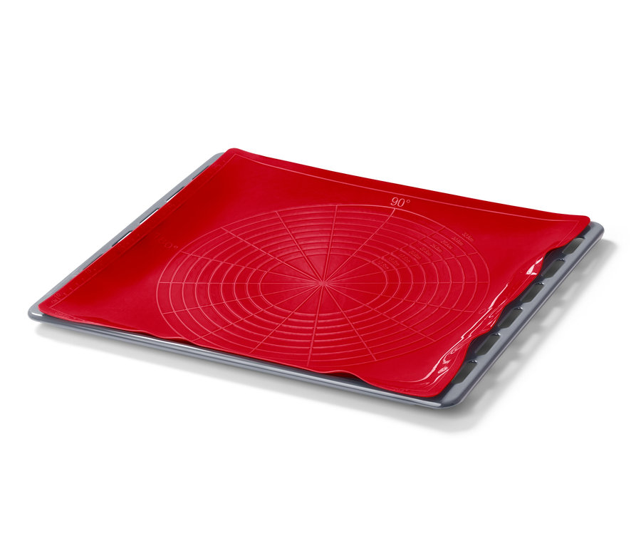 Un tapis de cuisson réutilisable rouge sur une plaque de cuisson grise.