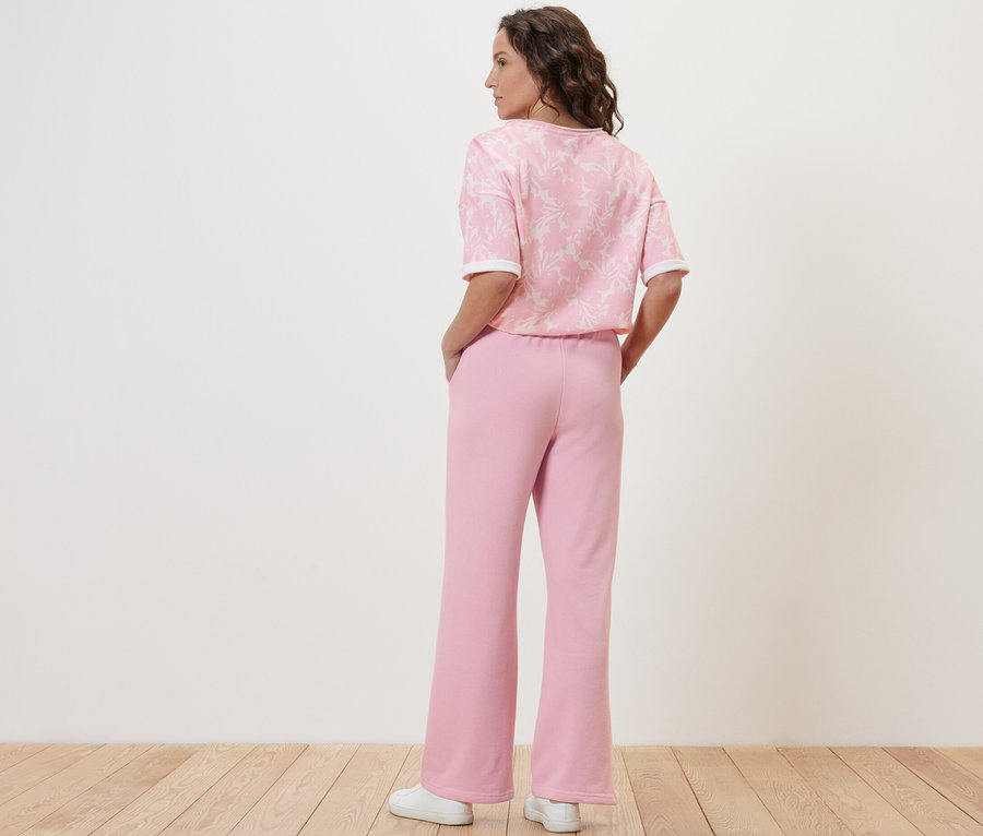 Une femme, vue de dos, porte un pantalon de jogging rose.