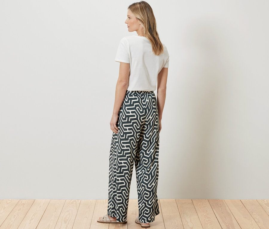 Une femme se tient dos à la caméra, portant un t-shirt blanc et un pantalon imprimé à enfiler avec effet Crinkle.