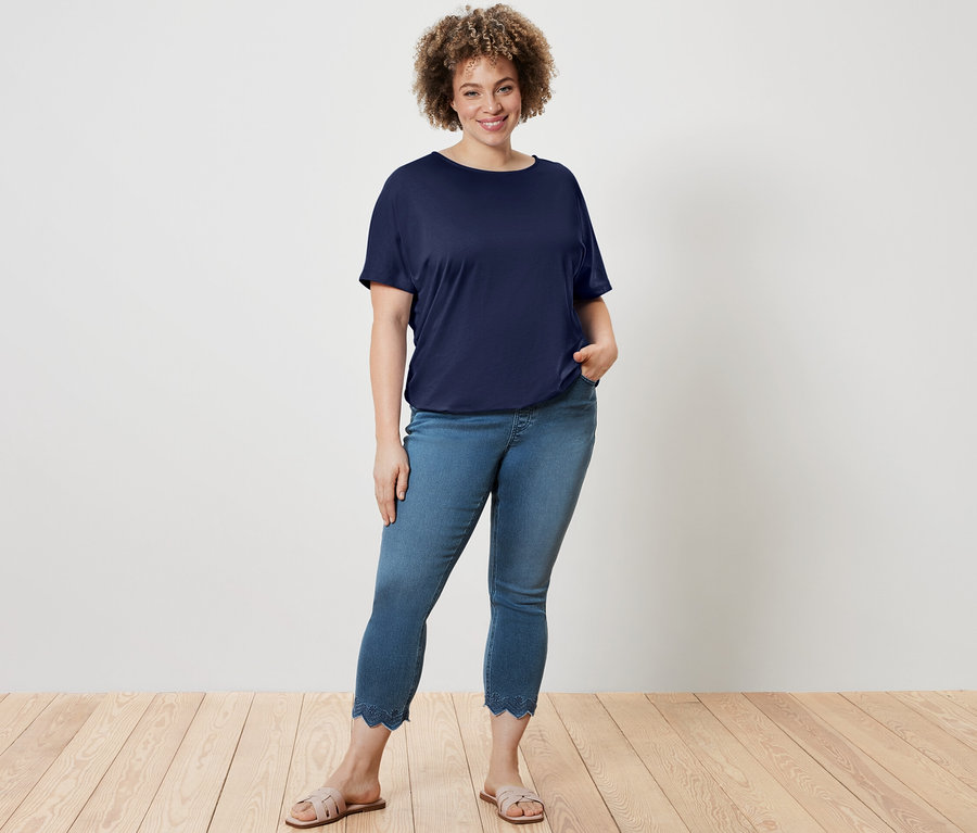 Femme posant en blouse bleu foncé et tregging 7/8 à broderie ajourée.