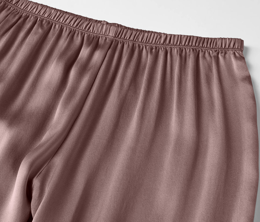 Détail d'un pantalon de pyjama en satin violet avec une taille élastique.