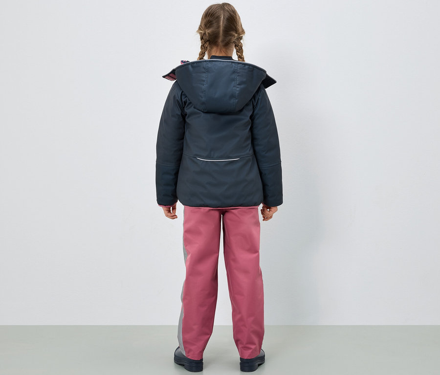Une fille vue de dos porte une veste bleu foncé et un pantalon de pluie rose pour enfants.