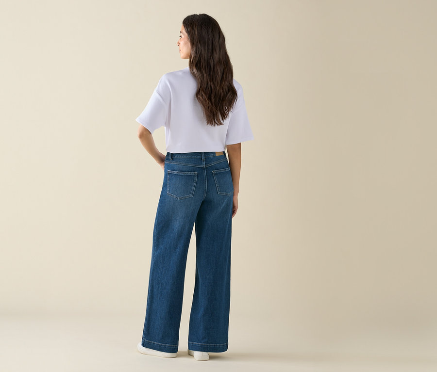 Femme posant en jean large et t-shirt blanc.