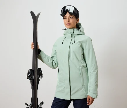 Femme tenant des skis et portant des lunettes de ski et une veste.