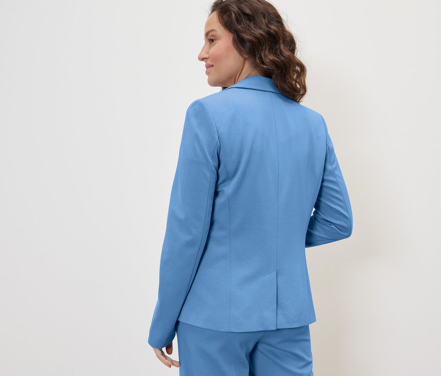 Femme posant en blazer en jersey bleu clair.