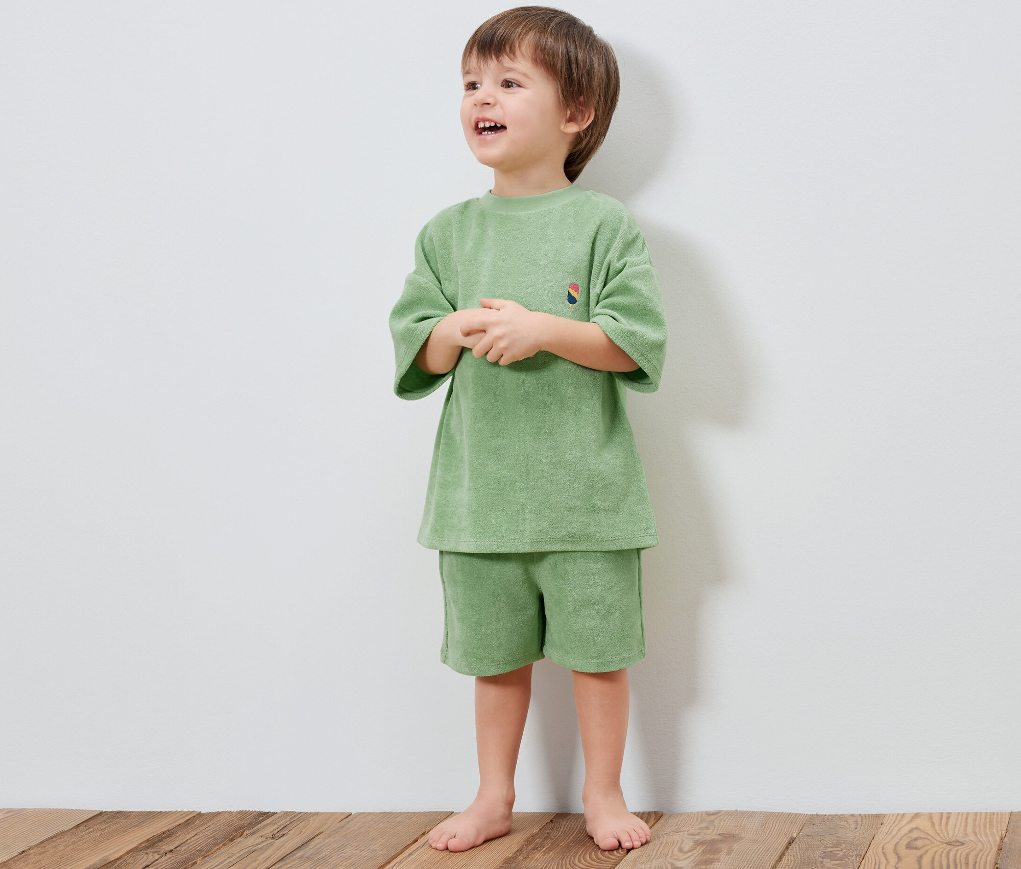 Un garçon porte un ensemble éponge pour enfants vert clair.