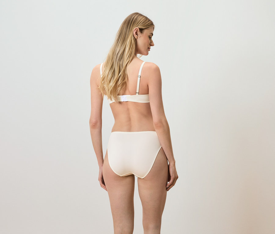 Vue arrière d'une femme aux cheveux blonds portant un soutien-gorge et une culotte beiges.