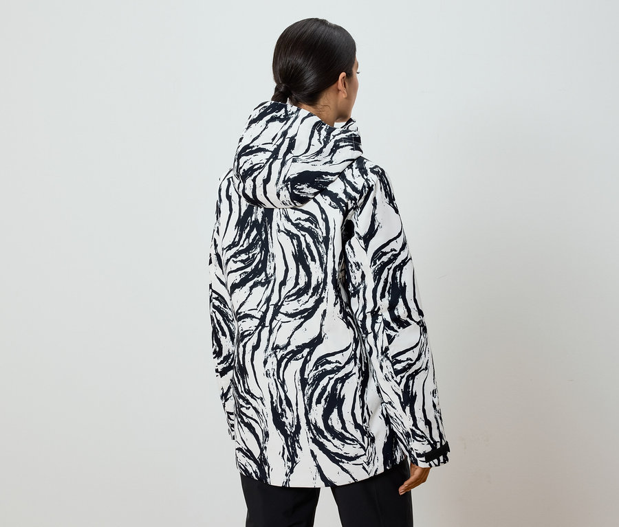 Vue arrière d'une femme portant une veste à capuche à motifs noirs et blancs et queue de cheval.