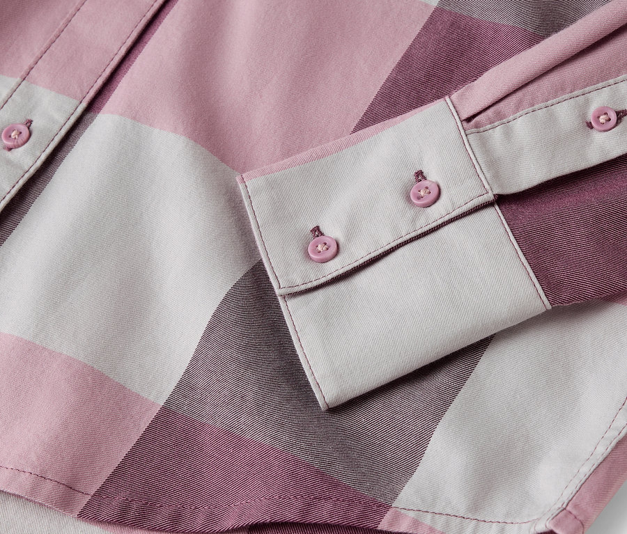 Détail d'une chemise à carreaux rose et blanche avec des boutons.