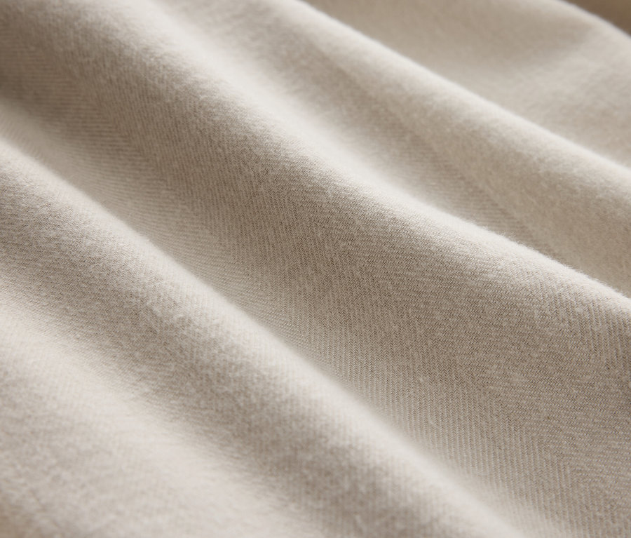 Gros plan d'un tissu crème avec de délicats plis.