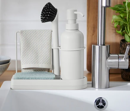 Organisateur d’évier avec brosse, chiffon et distributeur de savon près de l’évier.