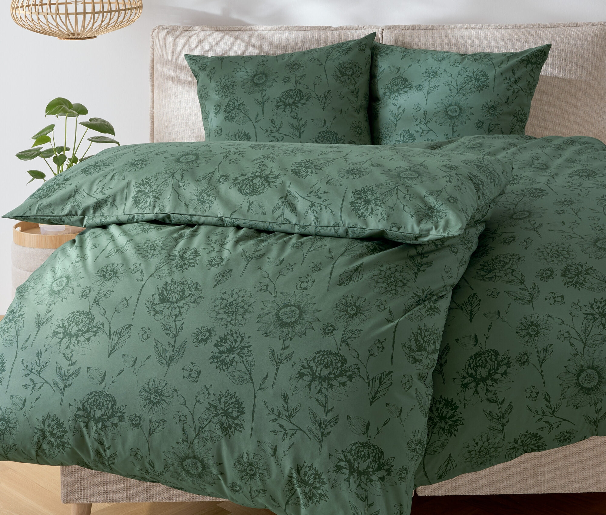 Linge de lit vert à motif floral sur un lit.