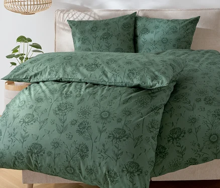 Linge de lit vert à motif floral sur un lit.