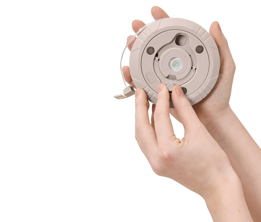 Une personne appuie sur le bouton d'une lampe ronde beige.