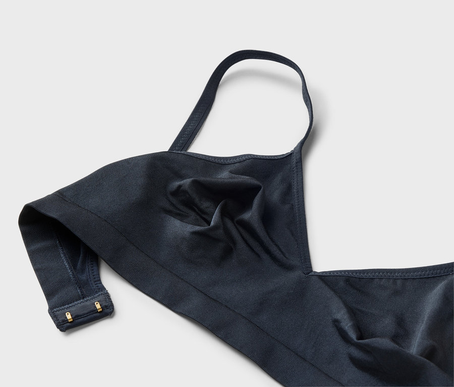 Gros plan d'un soutien-gorge bleu marine avec une seule bretelle et des agrafes dorées.