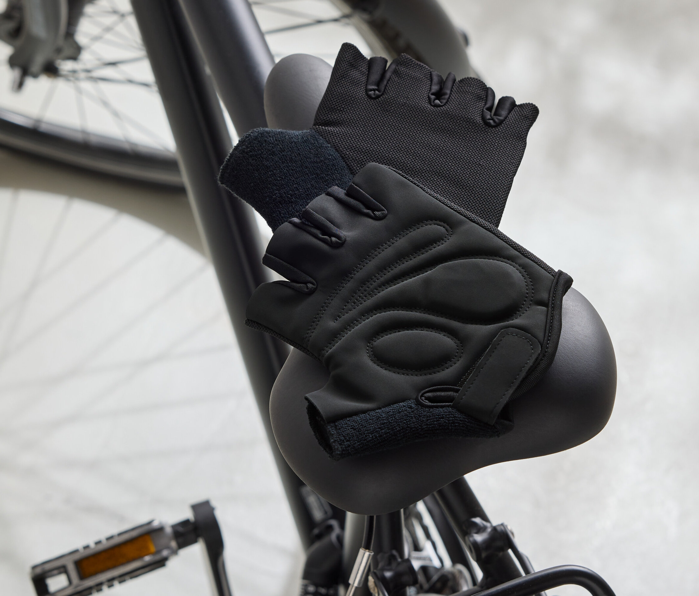 Deux gants de vélo noirs sont posés sur une selle de vélo noire.