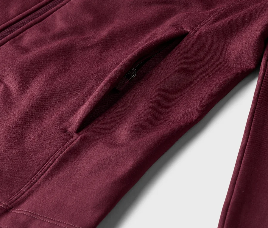 Gros plan d'une veste bordeaux avec fermeture éclair et poche latérale.