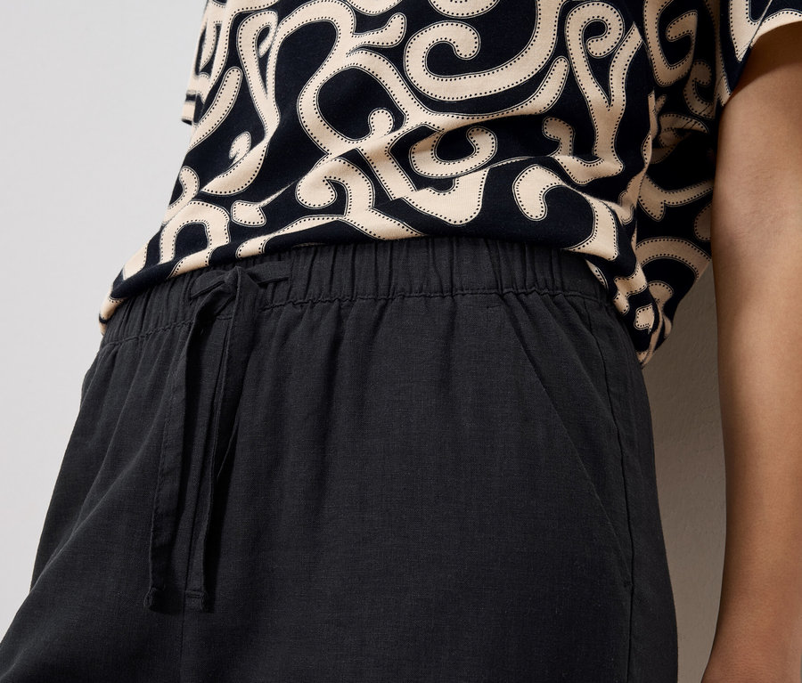Gros plan d'une personne portant un haut à motifs et un pantalon noir à cordon de serrage.
