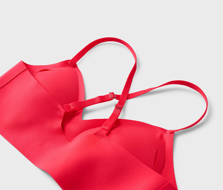 Gros plan d'un soutien-gorge rouge avec bretelles réglables sur fond gris.