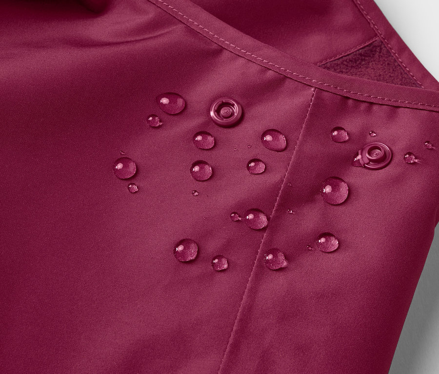 Gros plan d'un tissu bordeaux avec boutons-pression et gouttes d'eau.