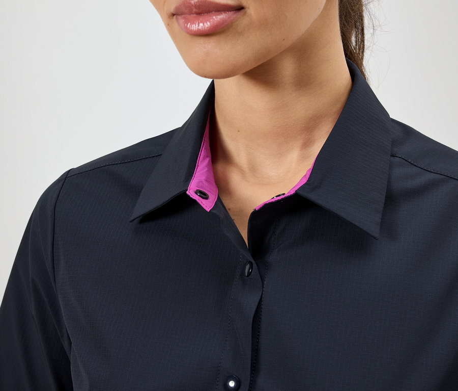 Gros plan d'une femme portant une chemise bleu foncé avec un col rose.