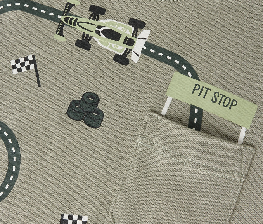 Impression sur un t-shirt Name it olive avec une piste de course, une voiture de course, une pile de pneus et des drapeaux.