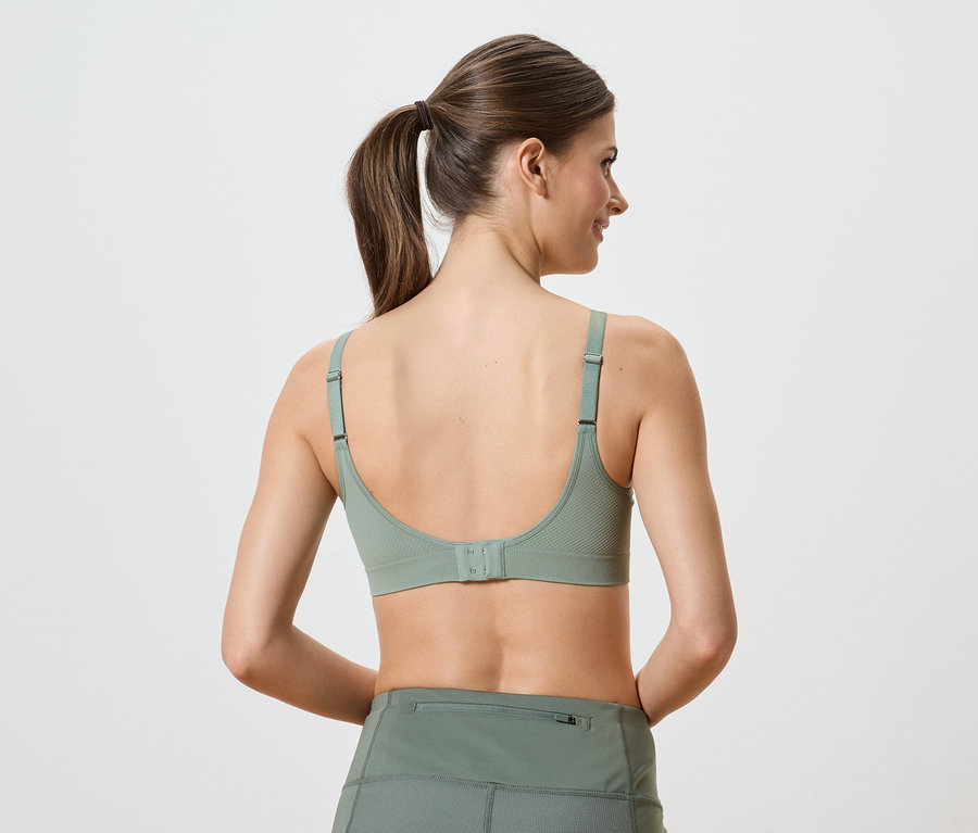 Vue arrière d'une femme portant un soutien-gorge de sport et un legging verts, les cheveux attachés en queue de cheval.