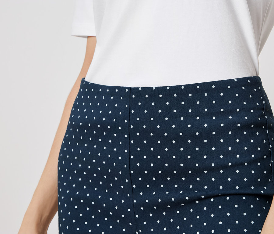 Gros plan d'une personne portant une robe bleu marine à pois blancs et un haut blanc.
